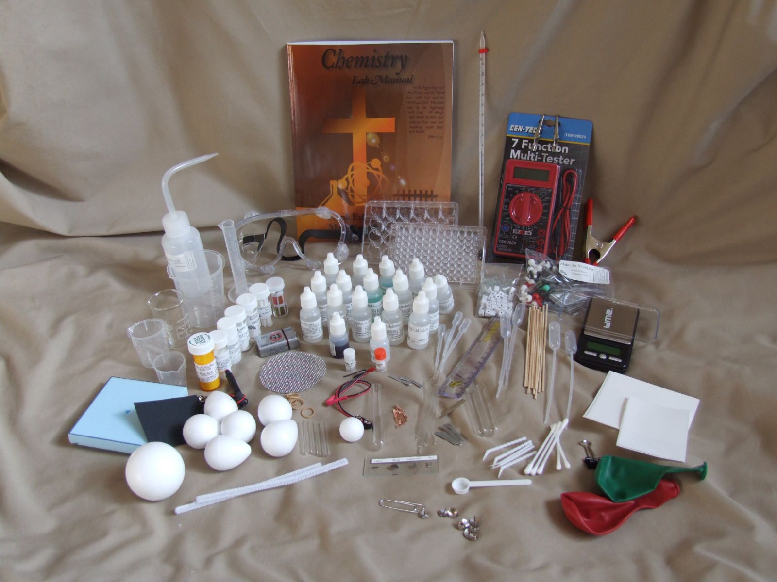 Every item in the Chemistry Kit laid out: manual, reagents, well plates, goggles and balance